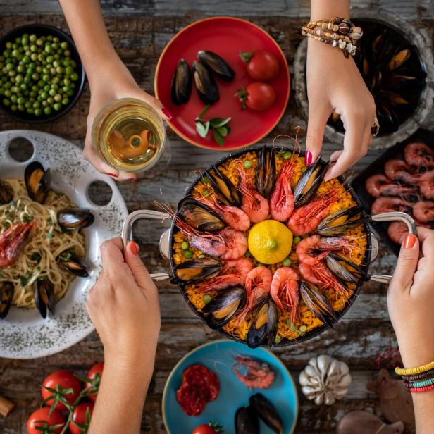 Paella mit Meeresfrüchten und Spaghetti Alle Vongole auf einem Tisch angerichtet.
