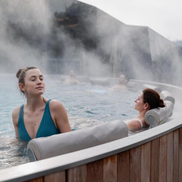 Eine Frau sitzt im Whirlpool und hat ihre Augen geschlossen.
