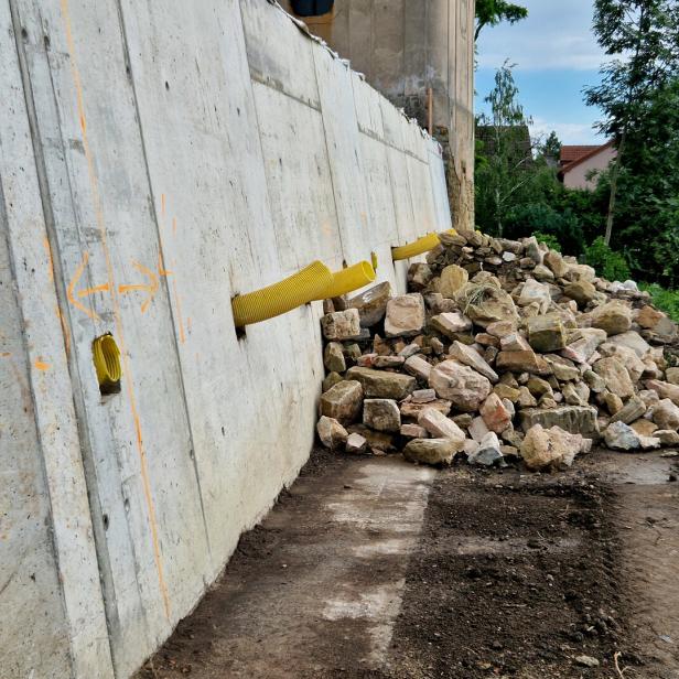 Hanggrundstück mit Mauer aus Beton und Drainage-Abläufen. 