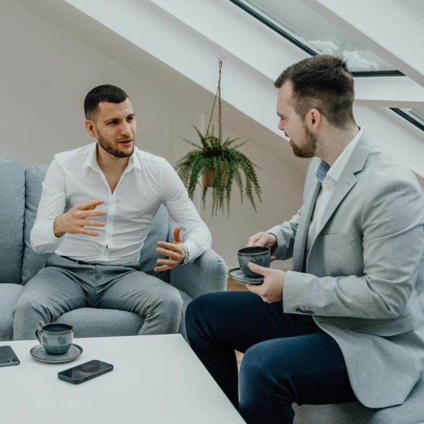 Zwei Männer sitzen auf einer Coach und diskutieren