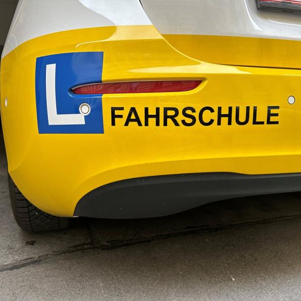 Das Heck eines gelben Fahrschulautos mit der Aufschrift „Fahrschule“.