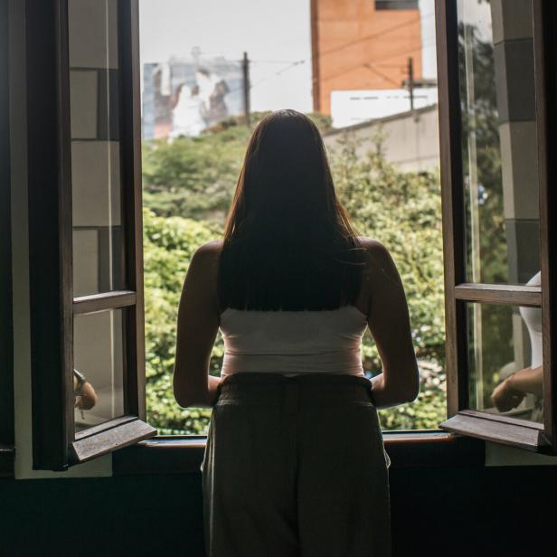 Eine junge Frau schaut aus dem Fenster.