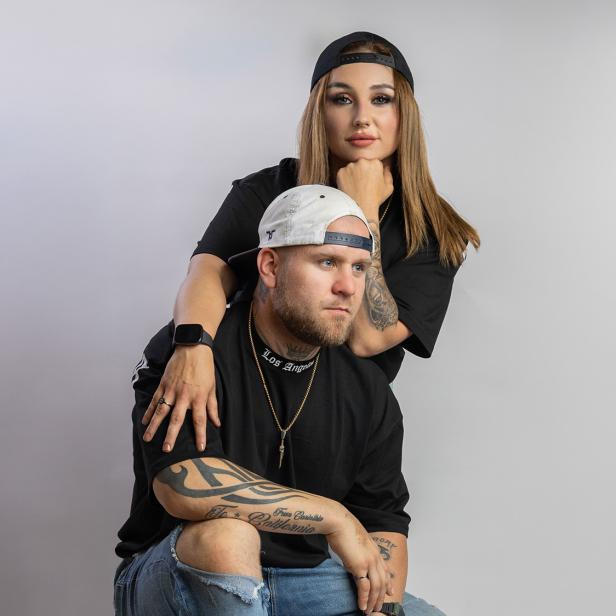 Ein Mann und eine Frau posieren mit Kappen vor der Kamera.