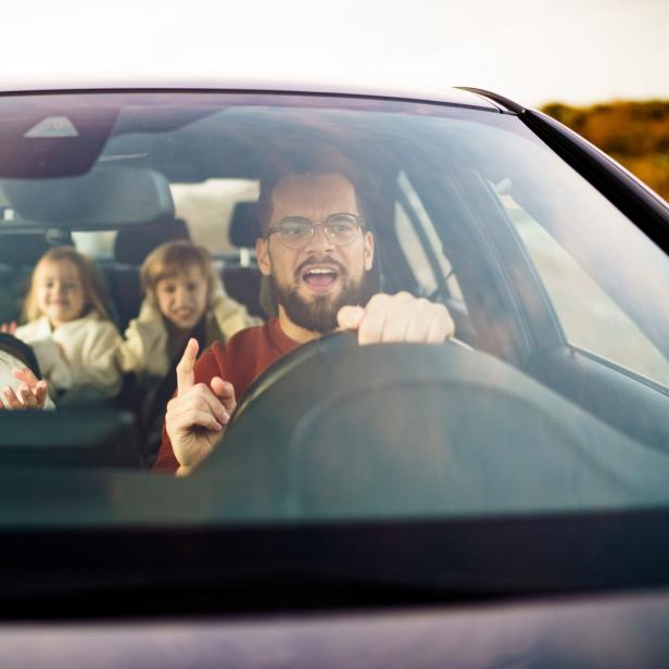 Mutter und Vater streiten sich, während die Kinder im Auto sitzen.