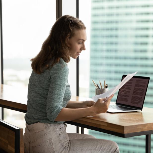 Serious student girl working on research paper, reviewing paper letter