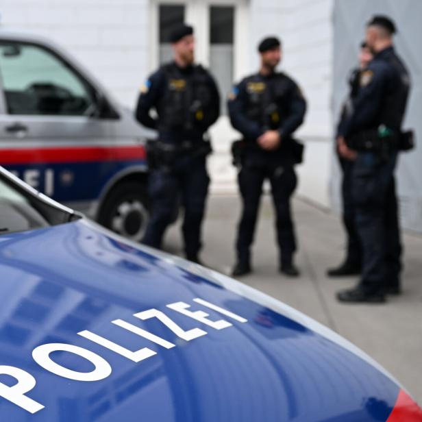 Polizeiautos, drei Polizisten im Hintergrund