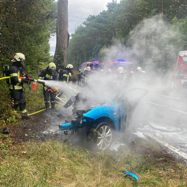 Feuerwehr-Einsatzkräfte löschen das brennende Unfallwrack