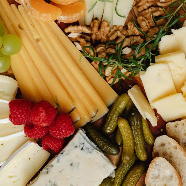 Eine Platte mit verschiedenen Käsesorten, Gemüse, Obst und Brot.