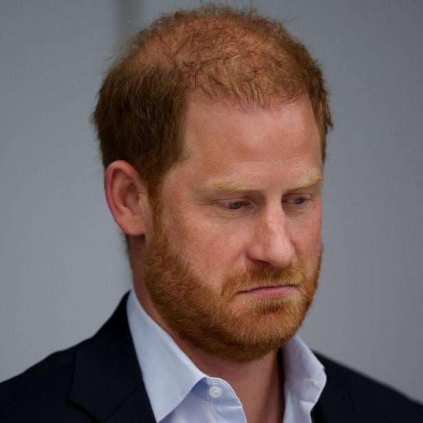 Prinz Harry mit Vollbart und Hemd blickt nach unten.