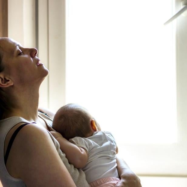 Eine müde, besorgte Mutter wiegt ein schlafendes Baby.