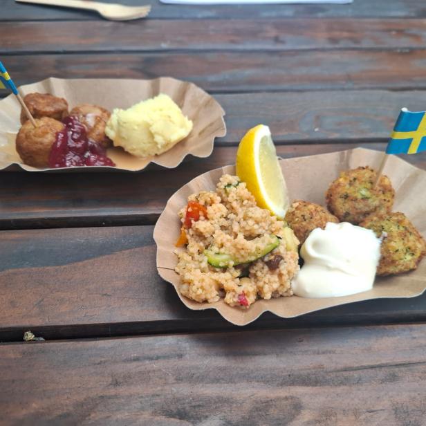 Zwei Pappteller mit schwedischen Spezialitäten, dekoriert mit kleinen Schwedenflaggen.