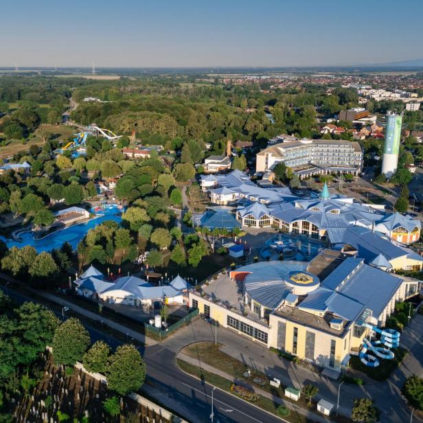 Luftaufnahme eines Resorts mit einem Wasserpark, umgeben von üppigem Grün und blauen Wasserflächen.