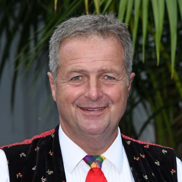 Norbert Rier, Sänger der Kastelruther Spatzen, trägt Trachtenweste und bunte Krawatte und lächelt in die Kamera.