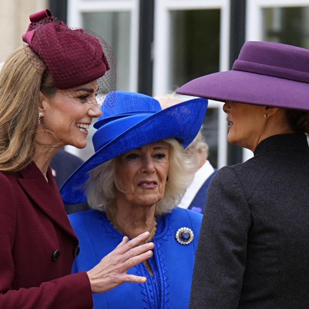 Prinzessin Kate, Königin Camilla und Melania Trump sind elegant gekleidet mit auffälligen Hüten und unterhalten sich im Freien.