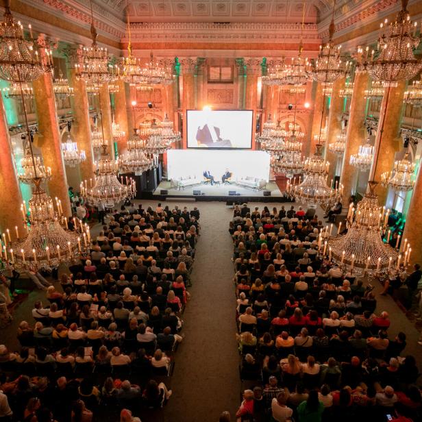 Ein großer Saal der Wiener Hofburg mit Lüstern und vielen Menschen.