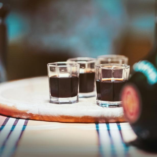 Eine Flasche Schnaps mit vier Gläsern auf einem Tisch, bereit zum Servieren.