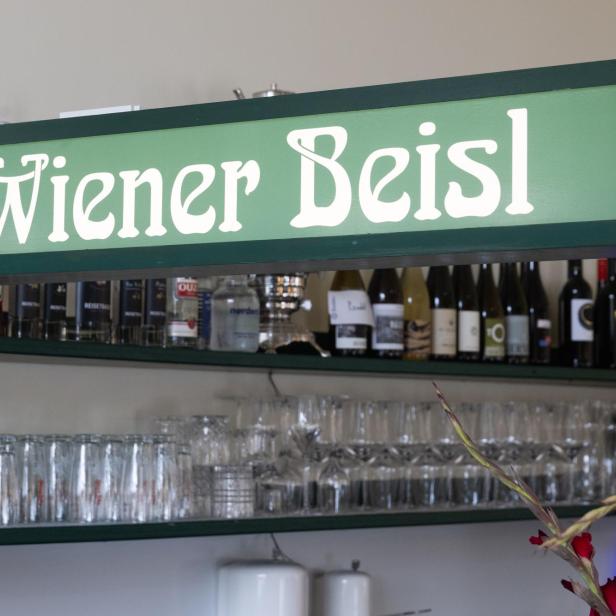 Ein Schild mit der Aufschrift „Wiener Beisl“ hängt über einer Bar.