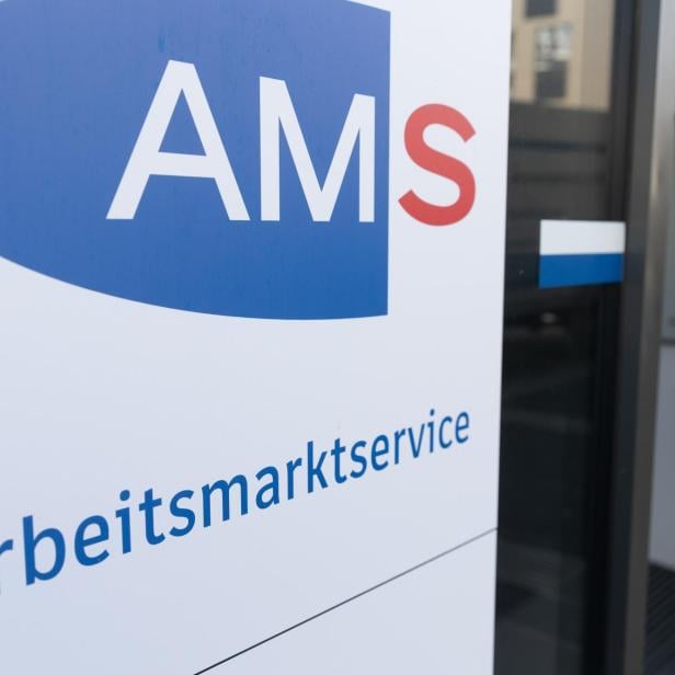 Ein Schild mit der Aufschrift „AMS Arbeitsmarktservice“ steht vor einem Eingang.
