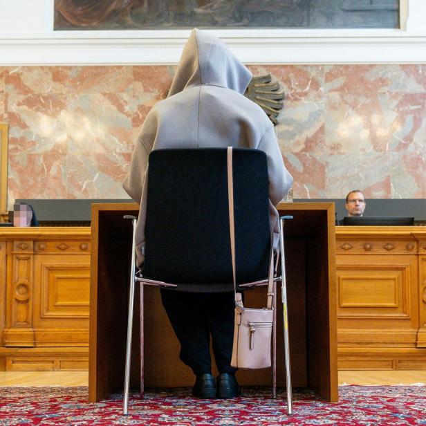 Frau sitzt mit dem Rücken zur Kamera in Gerichtssaal