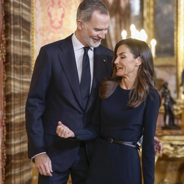 König Felipe und Königin Letizia stehen in einem eleganten Raum und schauen einander an.