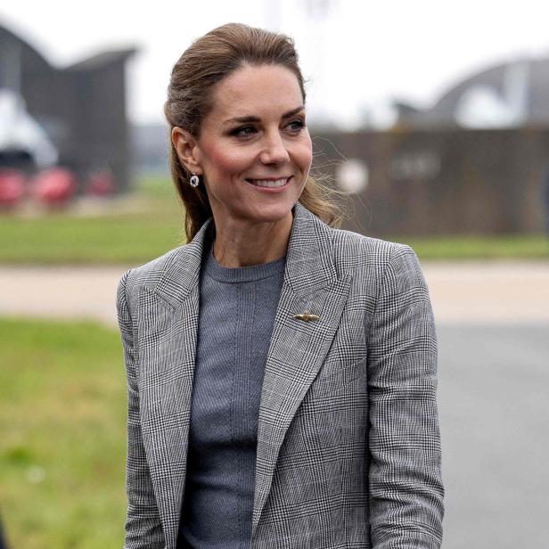 Prinzessin Kate lächelt in einem grauen Hosenanzug mit Karomuster.
