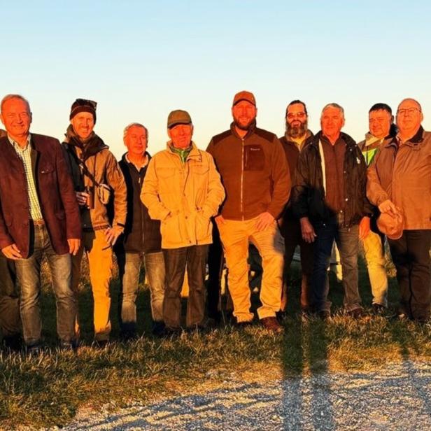 Eine Gruppe von Männern unterschiedlichen Alters steht im Freien bei Sonnenuntergang.