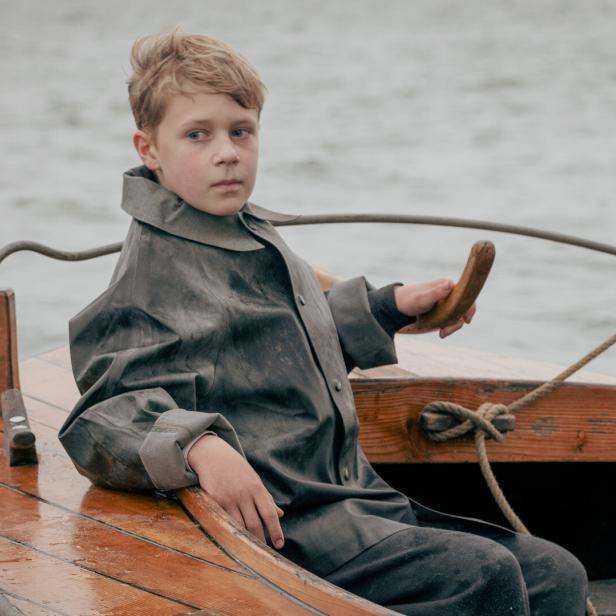 Ein zwölfjähriger Bub sitzt in einem Boot.