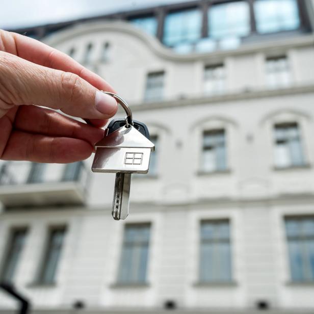Schönes Wohnhaus im Hintergrund, im Vordergrund hält eine Hand einen Schüssel.