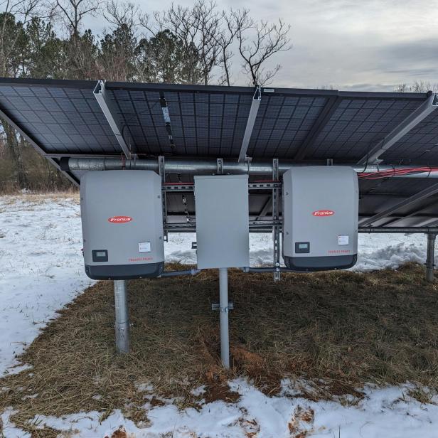 Zwei Solarpanels auf einem schneebedeckten Feld, umgeben von einer winterlichen Landschaft.
