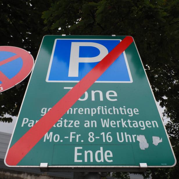 Grünes Verkehrsschild mit rotem Strich und Schrift