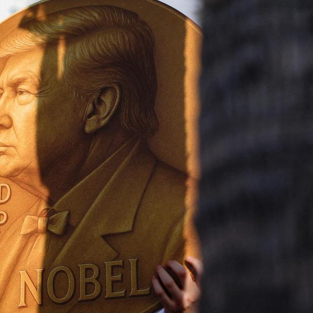 Eine Person hält eine große, goldene Medaille mit dem Porträt von Donald Trump und der Aufschrift "Nobel".