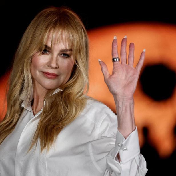 Nicole Kidman trägt ein weißes Hemd und winkt in die Kamera.