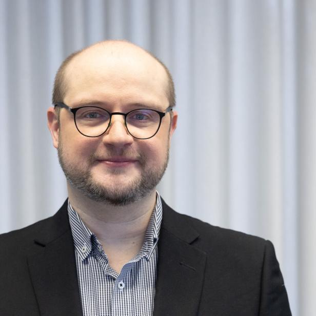 Dr. Ivan Milenkovic vor einem grauen Hintergrund.