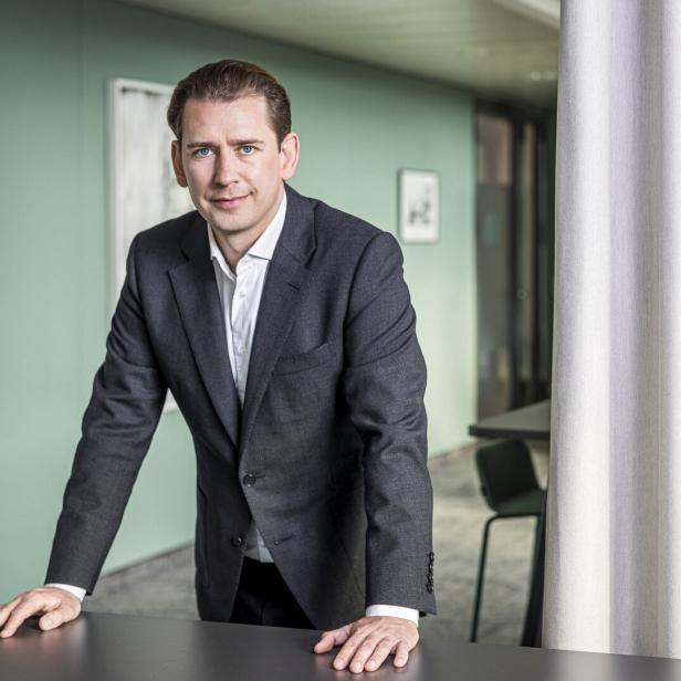 Sebastian Kurz im Anzug lehnt sich auf einen Tisch.