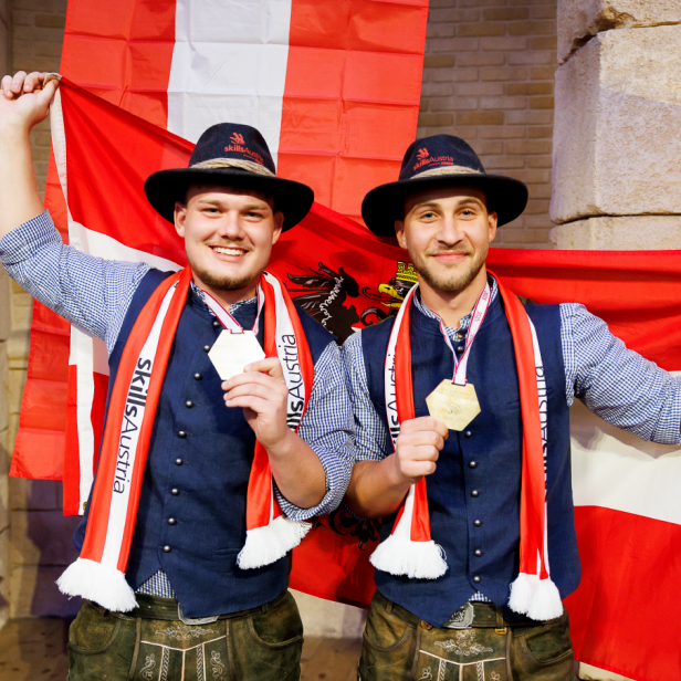 Zwei Männer halten die österreichische Flagge hoch. 