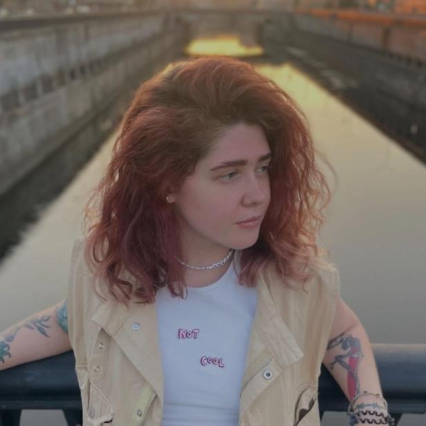 Vera Kravtsova posiert mit roten Haaren an einer Brücke