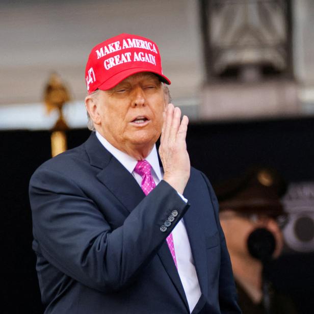 Donald Trump mit roter "Make America Great Again"-Kappe winkt mit erhobener Hand.