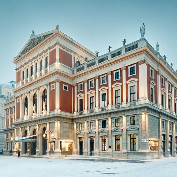 Historisches Gebäude mit klassizistischer Fassade und Statuen auf dem Dach bei winterlichem Wetter mit Schnee auf dem Boden.