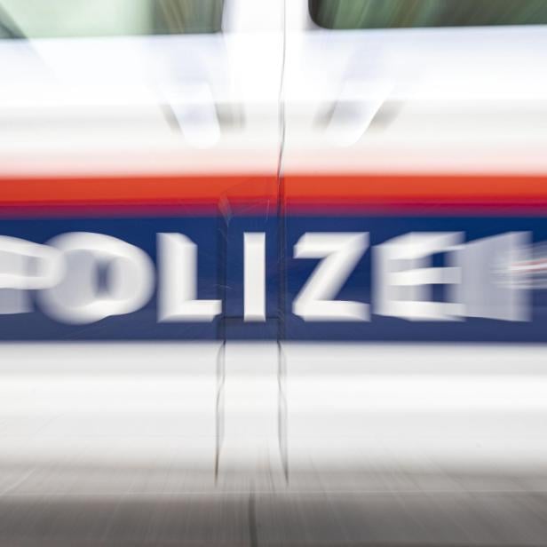 Verwischte Aufnahme eines Polizeiautos mit der Aufschrift "POLIZEI" in Weiß auf blauem Grund.
