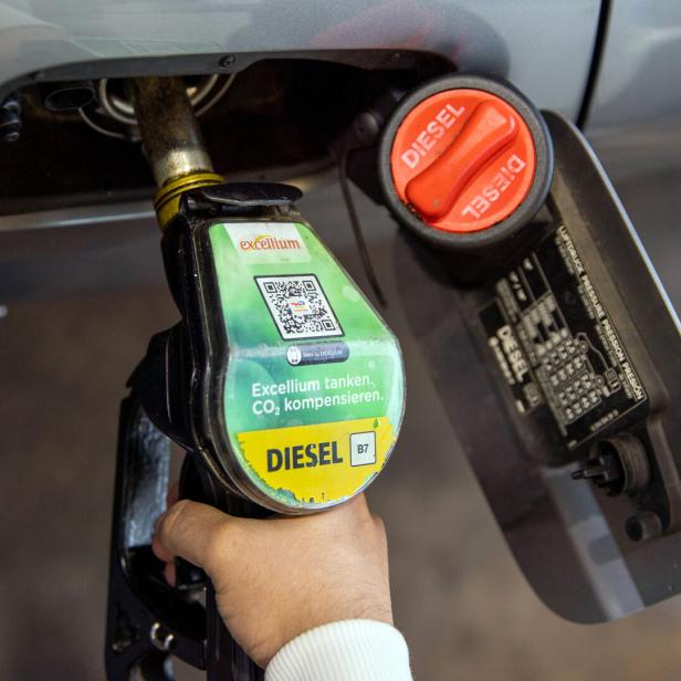 Eine Hand betankt ein Auto mit Diesel "Excellium", wobei der Tankdeckel geöffnet ist.
