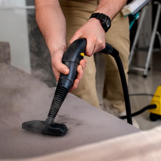 Amon Vertriebs GmbH: Der Dampfvollautomat für die Industrie ermöglicht eine effiziente, chemiefreie Reinigung in Profi-Bereichen. // Jemand stabsaugt ein Sofa.