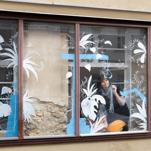 Schaufenster eines Grafikbüros in Wien Hernals. Die Illustratorin Nadine Kappacher zeichent mit Kreidestiften auf das Glas