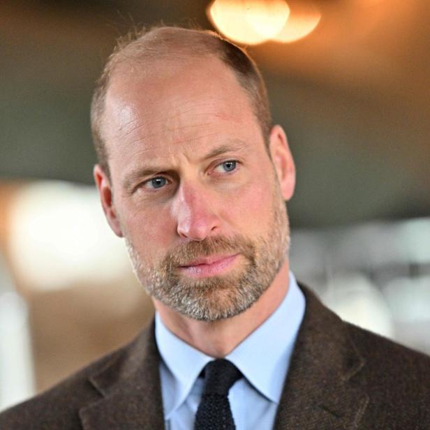 Prinz William mit Bart und braunem Sakko blickt zur Seite.