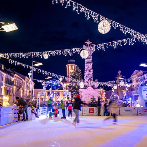 Die Aufnahme zeigt den weihnachtlich dekorierten Rathausplatz inklusive Eislauffläche in der Nacht.