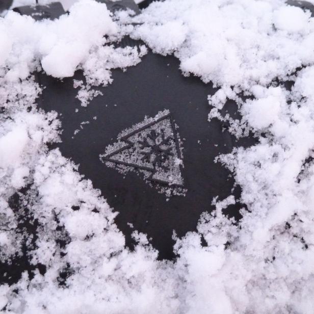 Schneeflockensymbol auf Autoreifen, mit Schnee runderhum