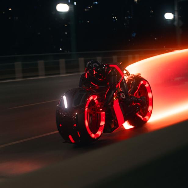 Ein Light Cycle aus dem Film Tron. Das Motorrad hat Räder ohne Speichen, ist rasant, der Fahrer verschmilzt damit und das Bike zieht einen Lichtstrahl hinter sich her.