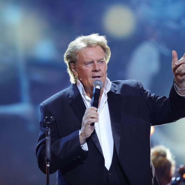 Howard Carpendale singt in ein Mikrofon und gestikuliert.