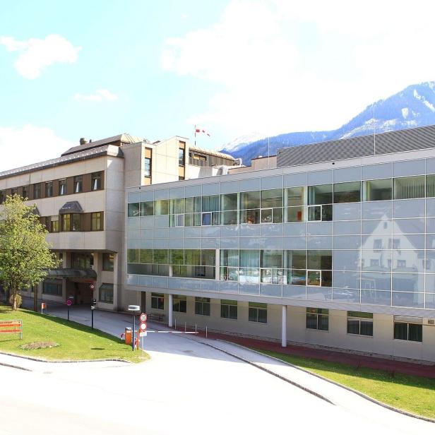 Spitalgebäude von außen, im Hintergrund Berge