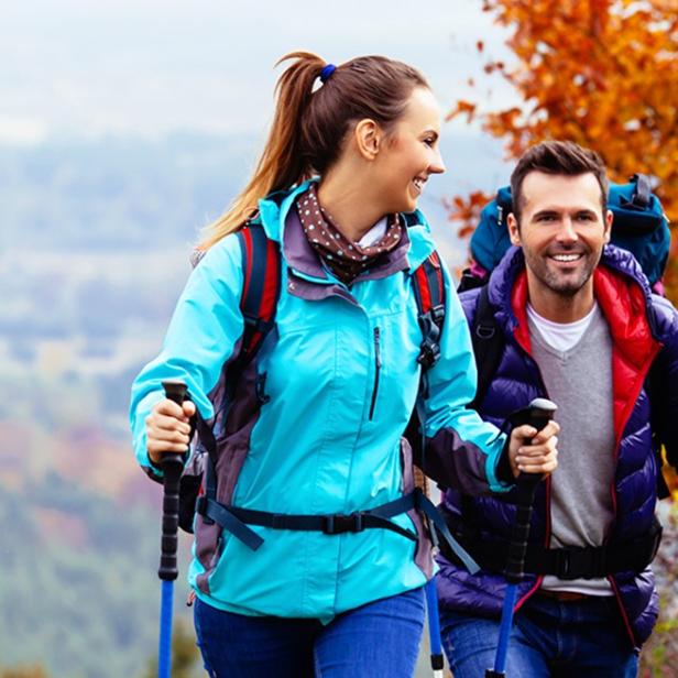 Ein Mann und eine Frau wandern in den Bergen, umgeben von herbstlich gefärbtem Gelände.