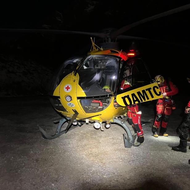 Bergrettung Werfen: Ein gelber ÖAMTC Hubschrauber im Dunkeln mit Einsatzkräften in rot gekleidet